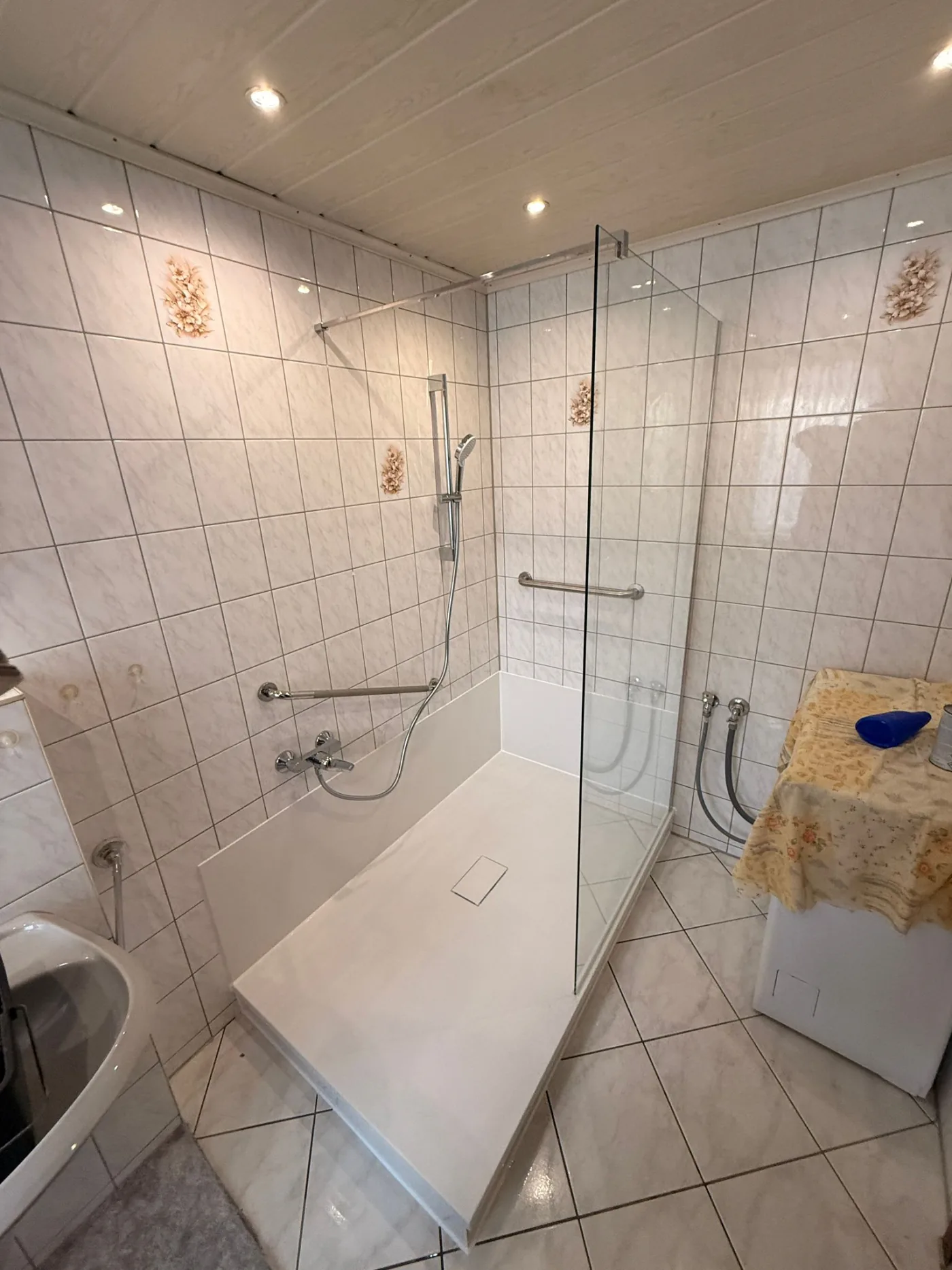 Helle barrierearme Dusche mit Glasabtrennung und Haltegriff